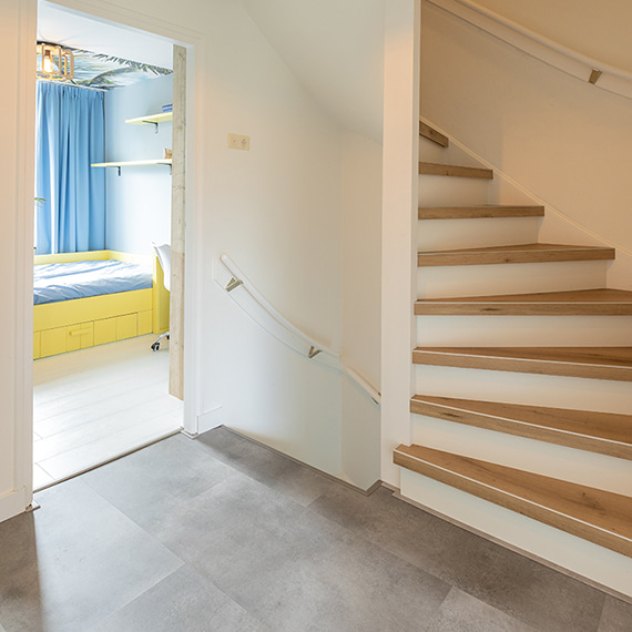 Quick-Step in De Grote Huisverbouwing - grijze pvc-vloer in gang en witte laminaatvloer in slaapkamer